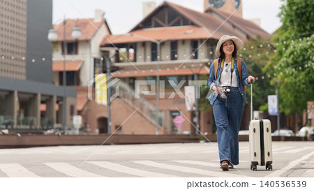 Asian woman traveling with suitcase and backpack exploring city for summer vacation tourism Asian woman traveling with suitcase and backpack exploring city for summer vacation tourism 140536539