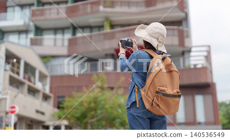 Rear view of Asian woman taking photo of modern building for urban travel photography Rear view of Asian woman taking photo of modern building for urban travel photography 140536549