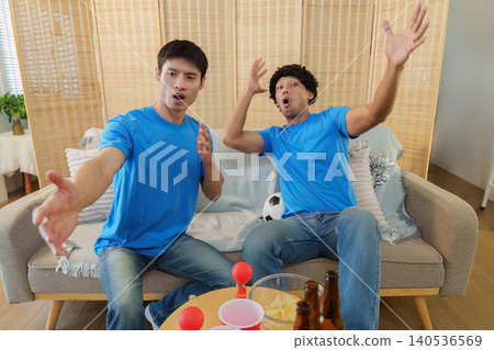 Two Asian men reacting emotionally while watching soccer game at home Two Asian men reacting emotionally while watching soccer game at home 140536569