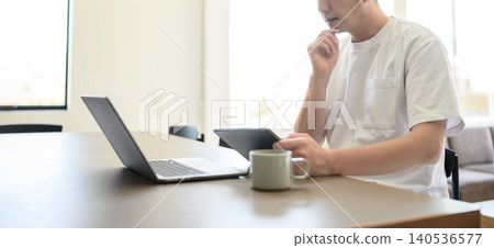 A man using a tablet and PC at home A man using a tablet and PC at home 140536577