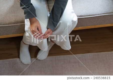 Person holding hands sitting on sofa for mental health and well-being 140536615