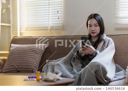 Asian woman feeling unwell at home using smartphone for health information 140536616