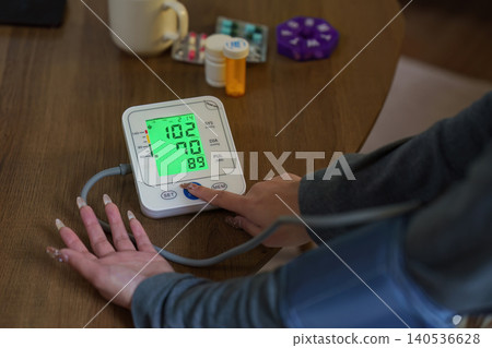 Woman checking blood pressure with digital monitor for home health care Woman checking blood pressure with digital monitor for home health care 140536628