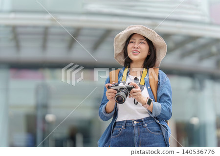 Asian woman tourist holding camera exploring urban city street Asian woman tourist holding camera exploring urban city street 140536776