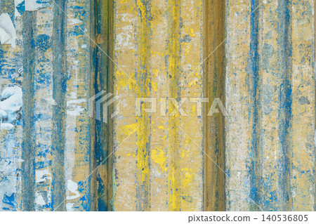 Weathered painted surface with blue and yellow vertical stripes, peeling layers, rough grunge detail. Useful as abstract background, design texture, or banner image, grunge design, creative projects 140536805