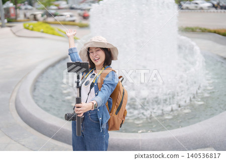 Asian woman vlogging with smartphone and camera outdoors 140536817
