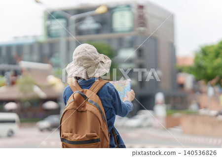 Asian woman tourist looking at map for navigation in city Asian woman tourist looking at map for navigation in city 140536826