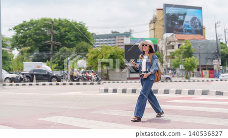 Asian woman traveler walking across city street crosswalk Asian woman traveler walking across city street crosswalk 140536827