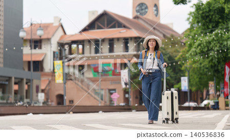 Asian woman tourist walking with luggage on urban street Asian woman tourist walking with luggage on urban street 140536836