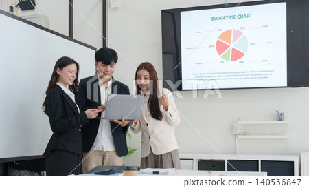 Asian business team reviewing budget pie chart on screen in office Asian business team reviewing budget pie chart on screen in office 140536847