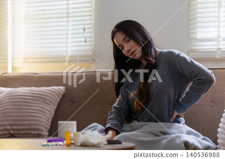 Asian woman suffering from back pain sitting on sofa at home 140536988