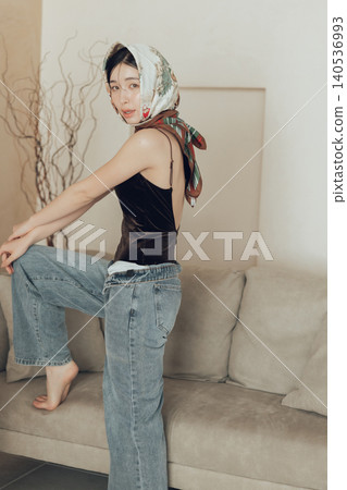 A woman wearing a swimsuit and denim scarf on her head. A woman wearing a swimsuit and denim scarf on her head. 140536993