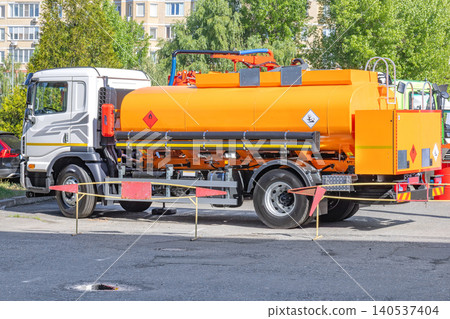 Truck with orange tank parked in a lot near buildings during daytime Truck with orange tank parked in a lot near buildings during daytime 140537404