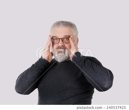 Mature bearded man adjusting eyeglasses and looking at camera isolated on gray background Mature bearded man adjusting eyeglasses and looking at camera isolated on gray background 140537425