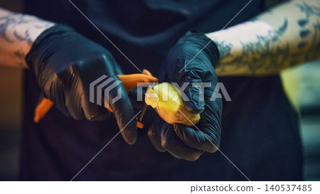 Close up of gloved hands peeling onion with vegetable peeler. Close up of gloved hands peeling onion with vegetable peeler. 140537485