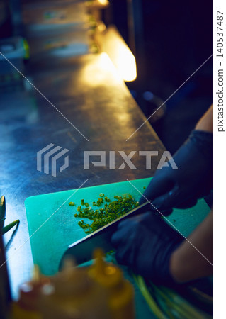 Chef chopping fresh green onions on cutting board in restaurant kitchen. Chef chopping fresh green onions on cutting board in restaurant kitchen. 140537487