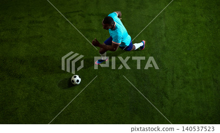 Top shot of soccer player running past ball on dark green field. Top shot of soccer player running past ball on dark green field. 140537523