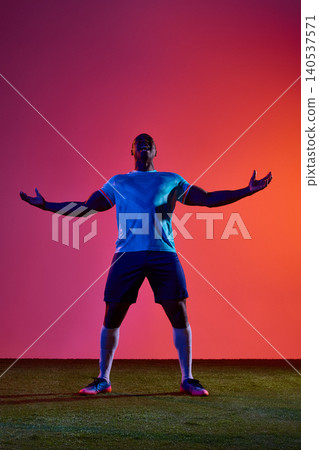 Soccer player shouting in victory with arms raised on studio field Soccer player shouting in victory with arms raised on studio field 140537571