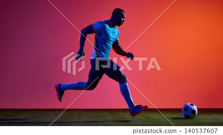 Soccer player running toward ball on vivid studio field background. 140537607