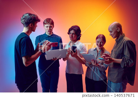 Young team discussing smartphones and tablets for digital product strategy in studio. Young team discussing smartphones and tablets for digital product strategy in studio. 140537671