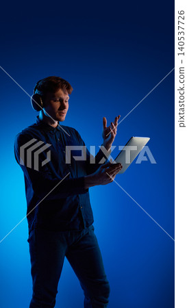 Man using tablet with gesture control in blue studio lighting. Man using tablet with gesture control in blue studio lighting. 140537726