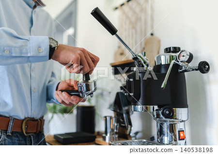 Man brewing espresso at home using a manual lever coffee machine 140538198