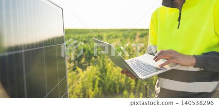 Engineer with laptop next to solar panel Engineer with laptop next to solar panel 140538296