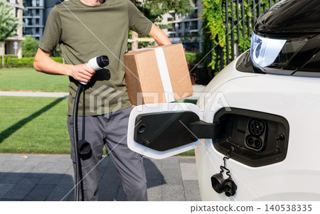 Driver with charging plug next to of electric van. Driver with charging plug next to of electric van. 140538335