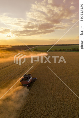 Combine harvester on the field at sunset. Aerial view. Combine harvester on the field at sunset. Aerial view. 140538389