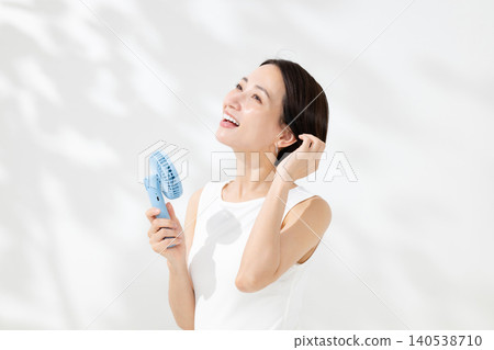 一位女士正用手持風扇為自己降溫。 一位女士正用手持風扇為自己降溫。 140538710