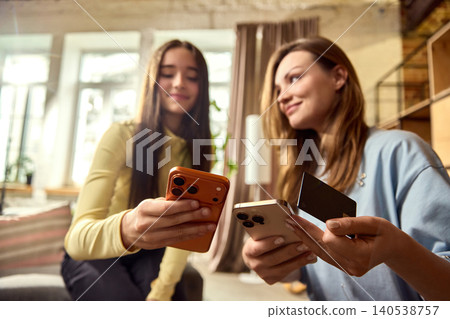 Mother teaching daughter mobile payment with card and smartphones at home. 140538757