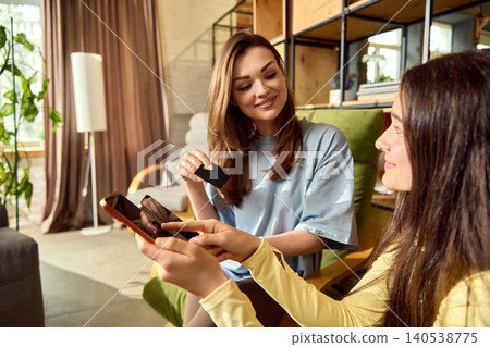 Mother helping daughter complete online payment using card and mobile phone. Mother helping daughter complete online payment using card and mobile phone. 140538775