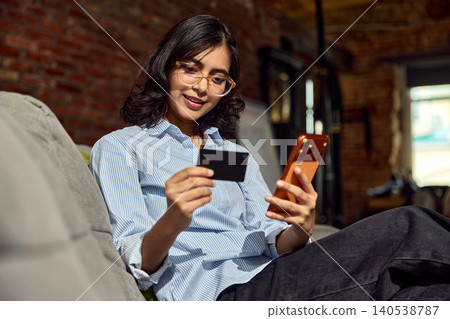 Woman using phone and bank card for secure mobile money transfer. Woman using phone and bank card for secure mobile money transfer. 140538787