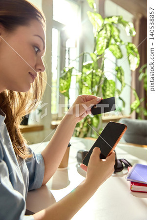 Smiling woman making money transfer with smartphone and bank card Smiling woman making money transfer with smartphone and bank card 140538857