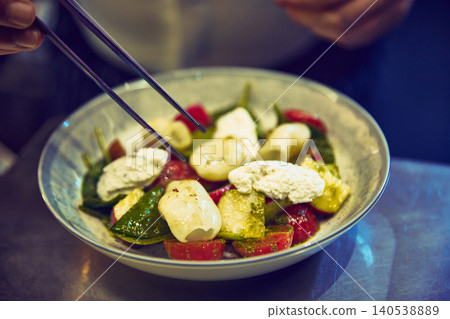 Chef arranging fresh vegetable salad with cheese in ceramic bowl Chef arranging fresh vegetable salad with cheese in ceramic bowl 140538889
