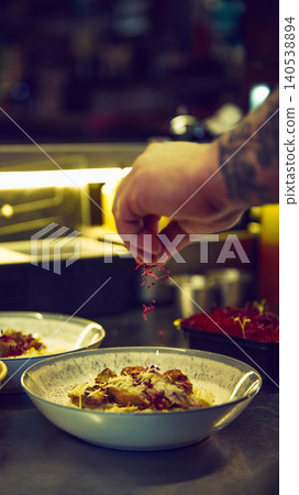 Chef adding microgreens to creamy chicken pasta bowl during dinner service. Chef adding microgreens to creamy chicken pasta bowl during dinner service. 140538894