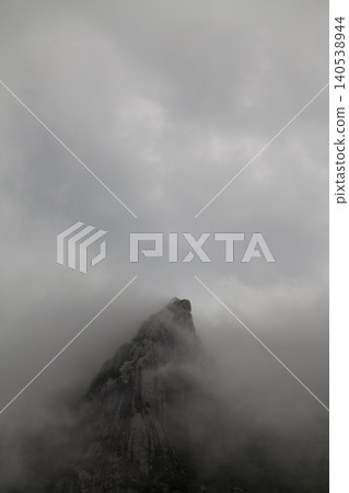 Cloud Covered Mountain Peak Landscape. Scenic Mountain Peak Rising Through Mist and Clouds. 140538944