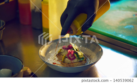 Chef adding spicy sauce to savory toast appetizer in restaurant kitchen Chef adding spicy sauce to savory toast appetizer in restaurant kitchen 140539062