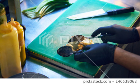 Chef spreading savory cream on toast with spoons in restaurant kitchen. 140539068