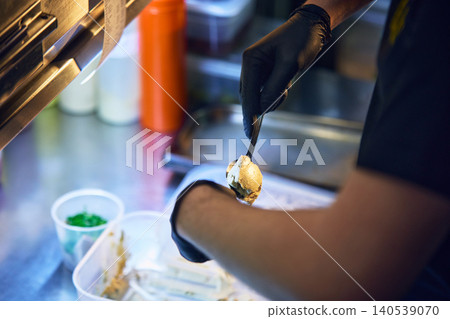Chef placing cream topping on toasted bread with tweezers in kitchen Chef placing cream topping on toasted bread with tweezers in kitchen 140539070