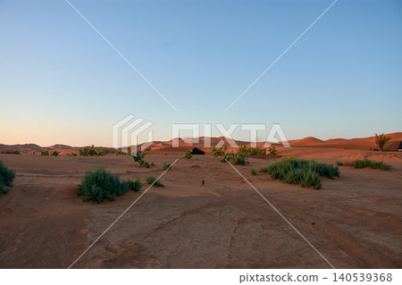 Reddish sand dunes stretch out beneath a clear blue sky in the Merzouga Desert in Morocco. Reddish sand dunes stretch out beneath a clear blue sky in the Merzouga Desert in Morocco. 140539368