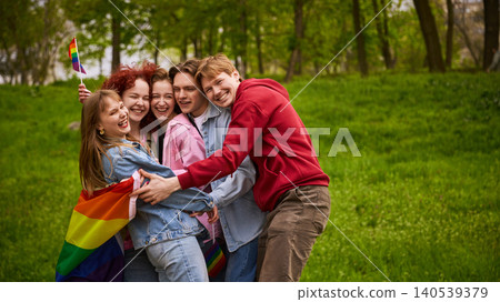 Happy group of young friends hugging with rainbow flag in park 140539379