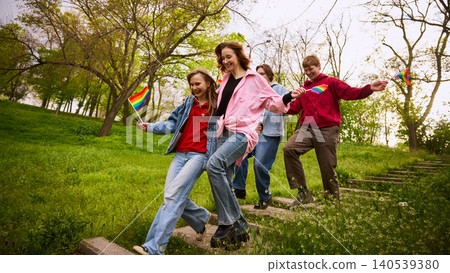 Young friends walking down park steps with rainbow flags. 140539380
