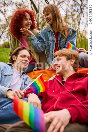 Young friends laughing with rainbow flags in sunny park close up. 140539382