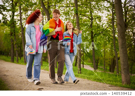 Smiling young people carrying rainbow flags during outdoor pride walk 140539412