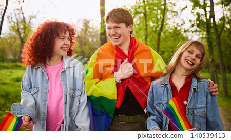 Happy young friends with rainbow flags walking together in summer park. 140539413