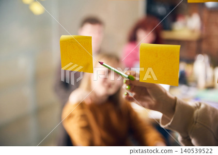 Hand pointing to sticky notes during business brainstorming meeting Hand pointing to sticky notes during business brainstorming meeting 140539522