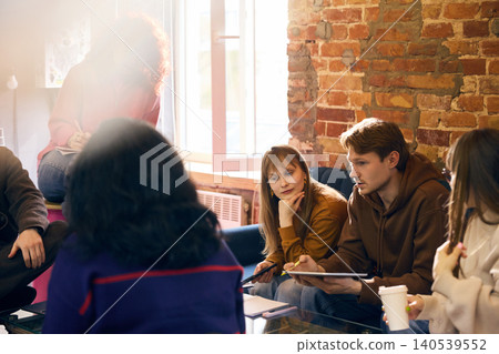 Business team sharing ideas during informal office meeting near brick wall. Business team sharing ideas during informal office meeting near brick wall. 140539552