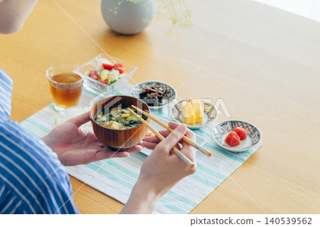 一位年輕女子在喝味噌湯當早餐時，雙手在鏡頭前。 140539562