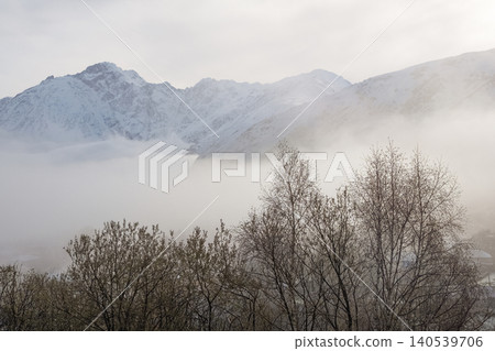Snow-capped peaks rise above swirling mist 140539706